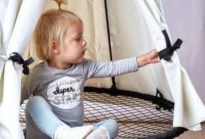 Barn leger i en Sort Sansegynge med et hvidt telt
