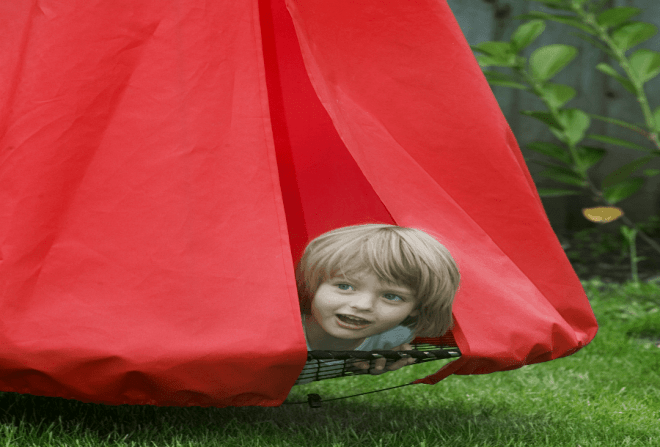 Pige kigger ud fra en Sansegynge med et rødt telt